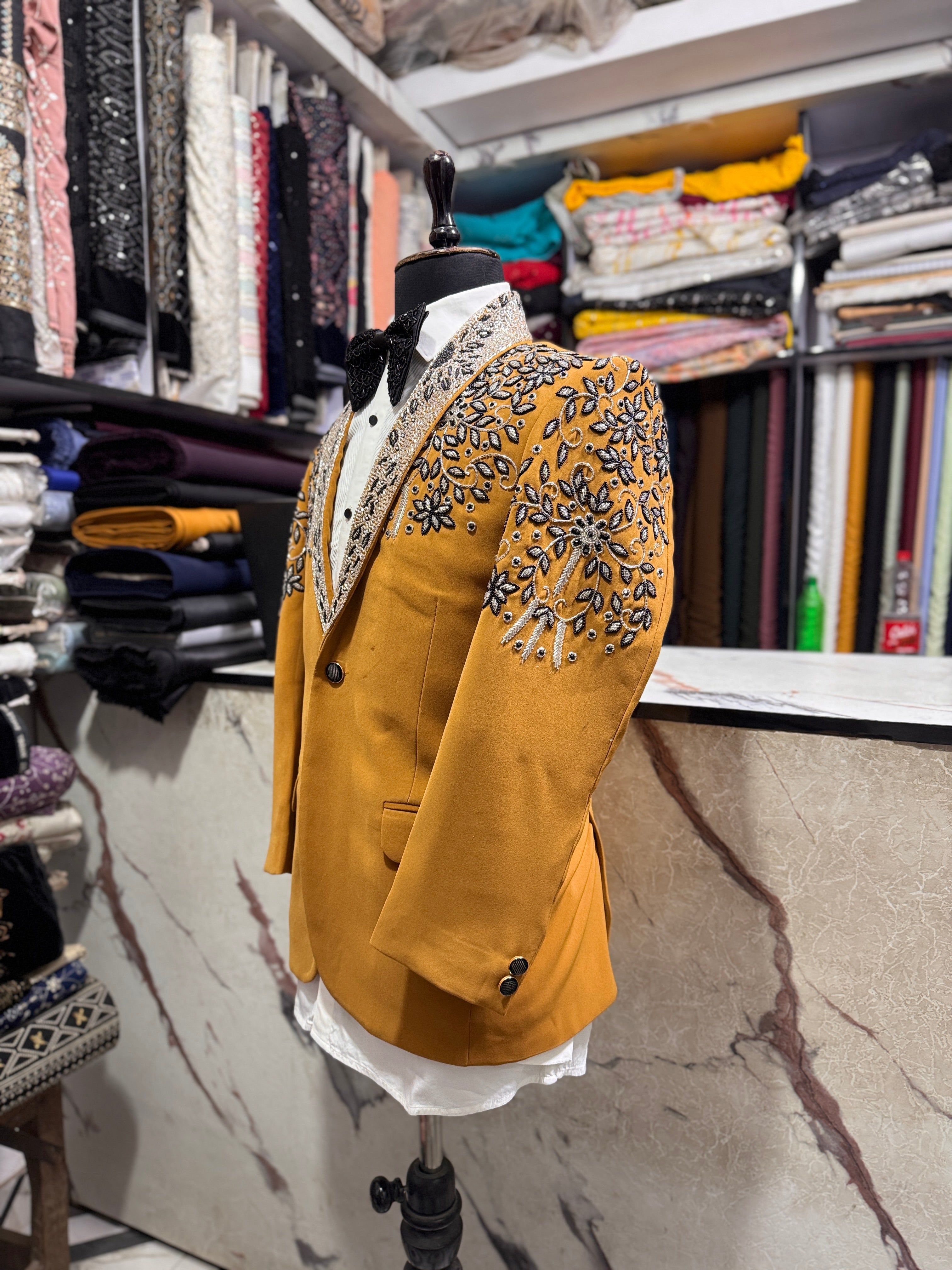 A front view of a man in a mustard-colored tuxedo suit with sparkling crystal embellishments on the blazer.

