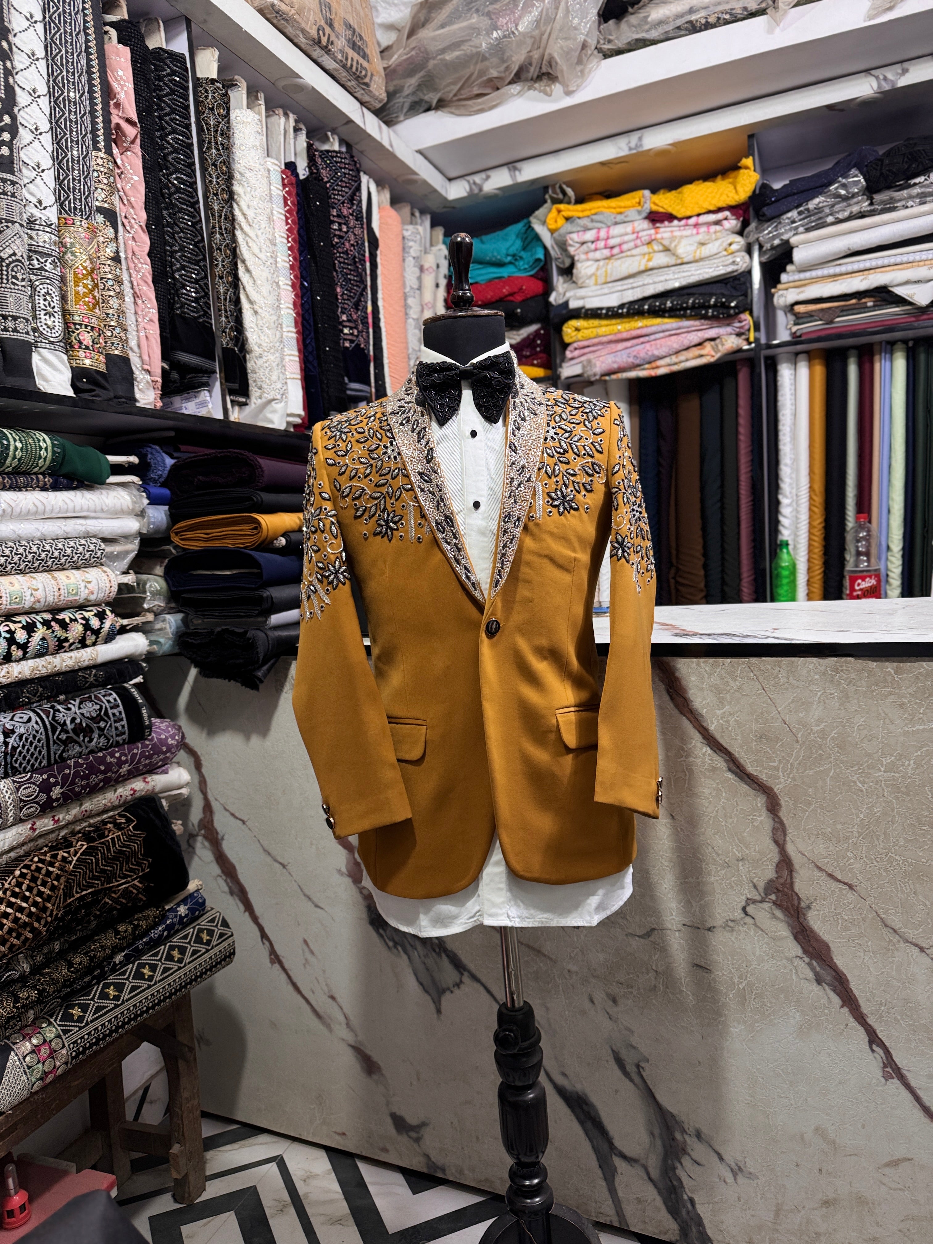 A front view of a man in a mustard-colored tuxedo suit with sparkling crystal embellishments on the blazer.

