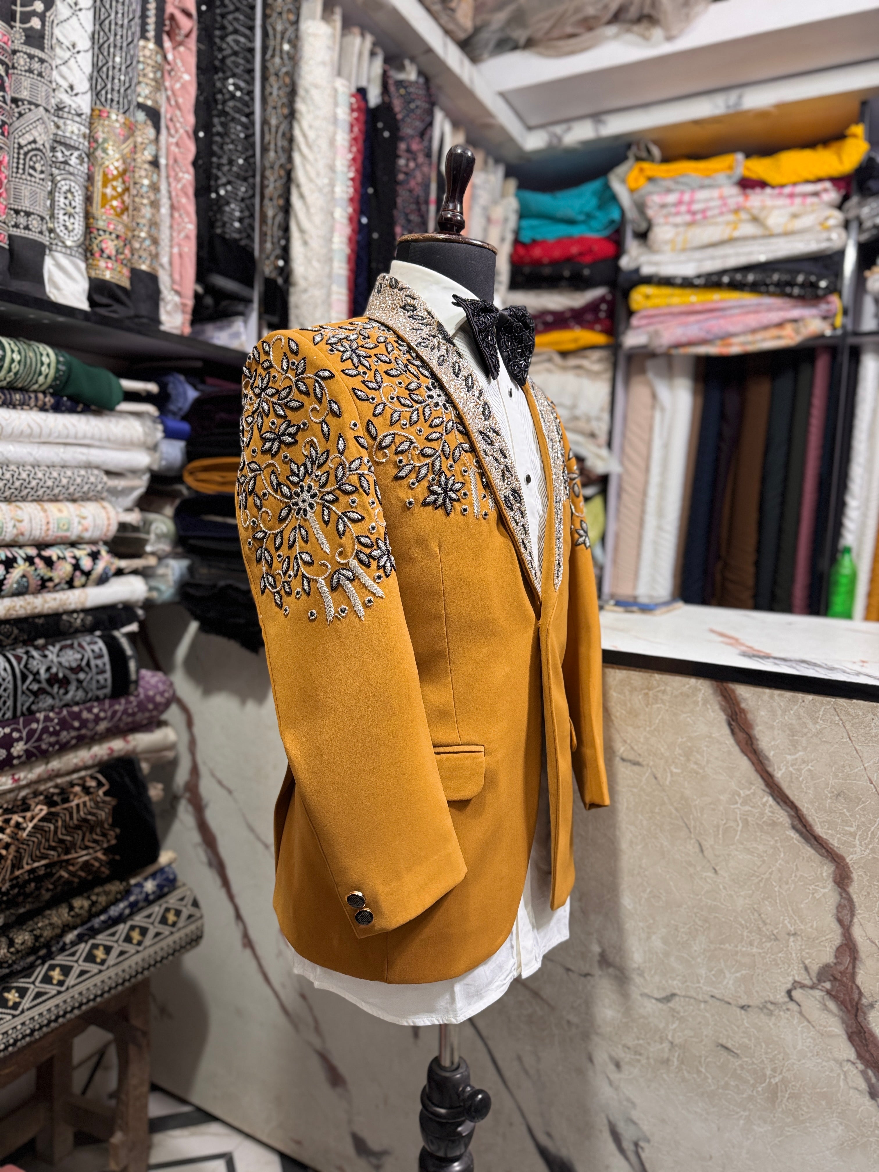 A front view of a man in a mustard-colored tuxedo suit with sparkling crystal embellishments on the blazer.

